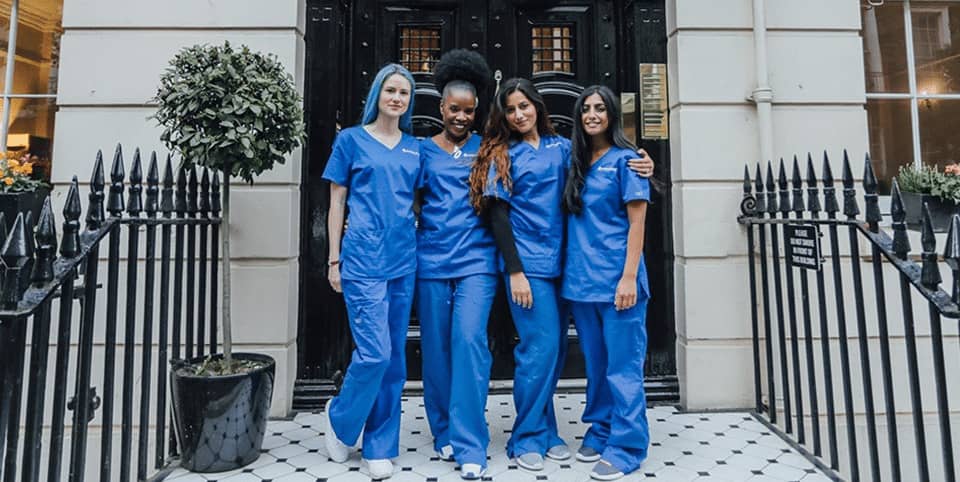 Four nurses in blue scrubs outside a Georgian clinic entrance at our Harley Street clinic, EMface facial toning London